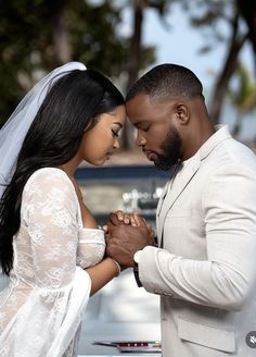 a man and woman standing next to each other in front of a car holding hands