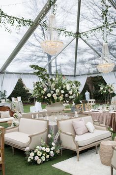 a tented area with couches, chairs and tables set up for an event