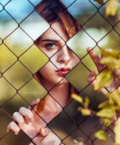 a girl looking through a fence with her hand on the fence and an inscription in arabic