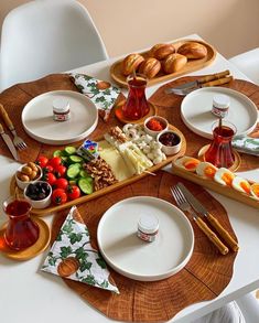 the table is set with plates, silverware, and bread on it as well as condiments