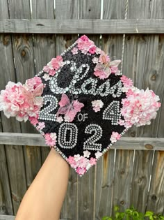 someone is holding up a graduation cap decorated with pink flowers and butterflies on the front