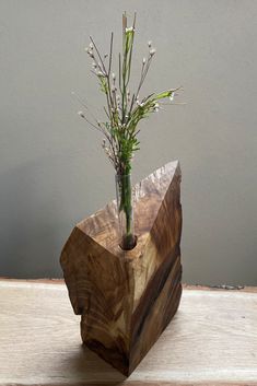 a vase with flowers in it sitting on a table next to a wooden block that has been cut into pieces