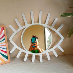 a woman taking a selfie in front of a mirror with an eye shaped frame