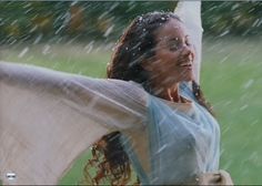 a woman standing in the rain with her arms around her body and holding an umbrella