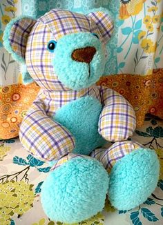 a blue teddy bear sitting on top of a bed next to colorful pillows and curtains