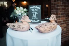 two wooden ducks sitting on top of a table next to a sign that says please say no more