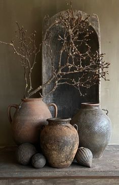 three vases are sitting on a shelf with branches in the middle and balls around them