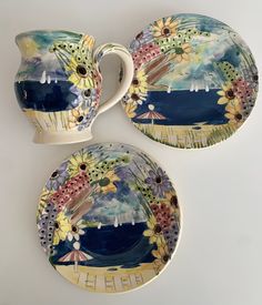 three plates and two cups with flowers painted on them