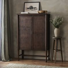 a tall wooden cabinet sitting next to a potted plant on top of a table