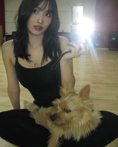 a woman is sitting on the floor with her dog and taking a selfie photo