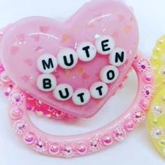 two pink and yellow heart shaped objects with words written on them, one is made out of plastic beads