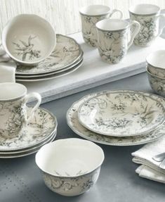 a table topped with lots of white dishes and cups on top of a gray counter