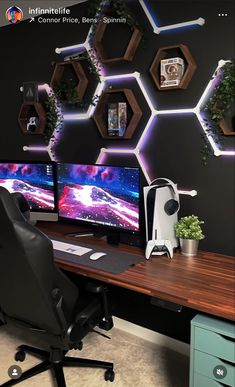 a computer desk with two monitors on it and some plants in front of the monitor