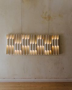 a wall sculpture made out of wood sticks with candles in the middle on top of it