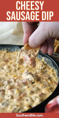 a hand holding a tortilla chip with cheese and sausage dip