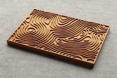 a wooden cutting board with wavy designs on the bottom and sides, sitting on a gray surface