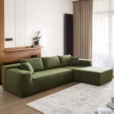 a living room with a large green couch and white rug in front of the window