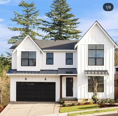 a white two story house with black garage doors on the front and side of it