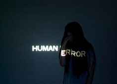 a woman standing in front of a neon sign that reads human error