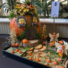 a display with pumpkins and fairy figurines in the shape of a house