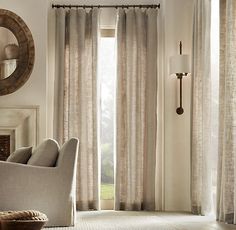 a living room filled with furniture and a large window covered in beige drapes