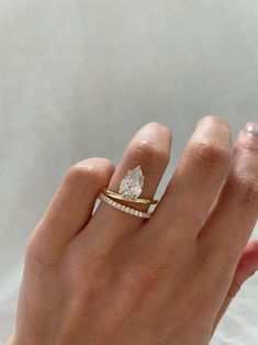 a woman's hand with a diamond ring on top of her finger and an engagement band