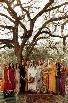 a group of women standing next to each other in front of a large oak tree