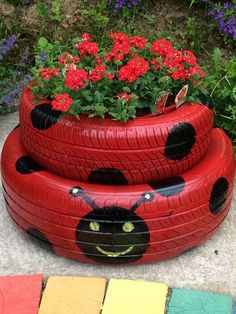 a planter made out of old tires is sitting on the ground next to flowers