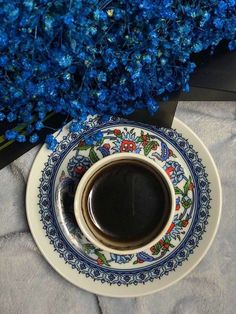 a coffee cup and saucer with blue flowers in the background