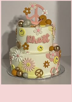 a three tiered cake decorated with flowers and peace signs