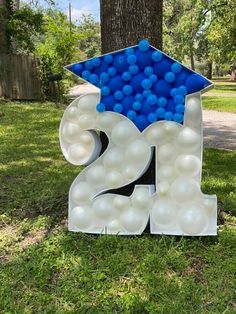 a graduation sign with balloons in the shape of numbers and a mortar cap on top