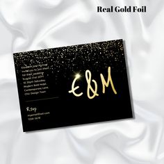 a black and gold business card with the word e & m written in gold on it