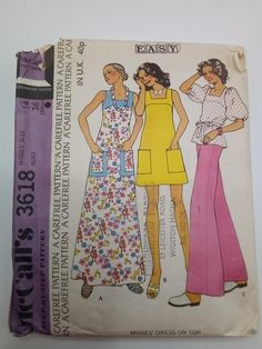 two women's aprons and dress sewing pattern on top of a piece of cloth