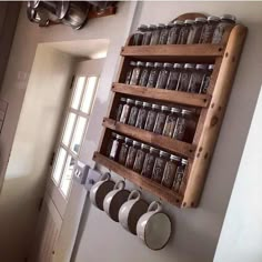 a wooden shelf with jars and spoons hanging on it's side next to a door