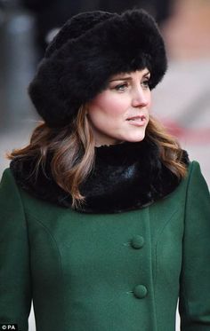 a woman wearing a green coat and black fur hat