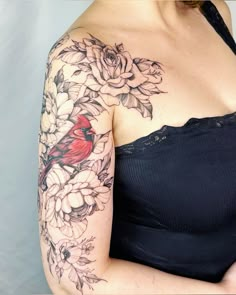 a woman's shoulder with flowers and a cardinal tattoo on her left arm,