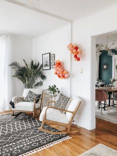 a living room with two chairs and a rug on the floor next to a potted plant