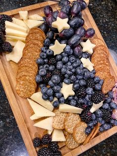 an assortment of crackers, grapes and cheese on a cutting board with blackberries