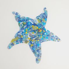 a blue and yellow mosaic glass starfish on a white background, with small circles around it