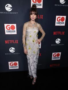 a woman in white dress standing on a red carpet with her hands on her hips