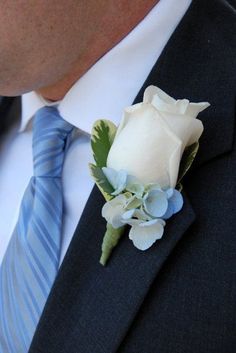 a man wearing a suit and tie with a boutonniere on his lapel