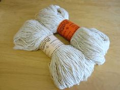 two skeins of white yarn sitting on top of a wooden table