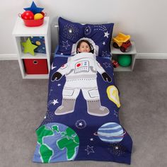 a little boy laying in bed with an astronaut themed comforter