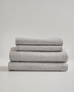 three sheets folded on top of each other in light grey linens, with one sheet folded