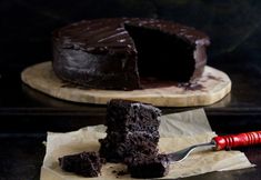 a piece of chocolate cake on a wooden cutting board