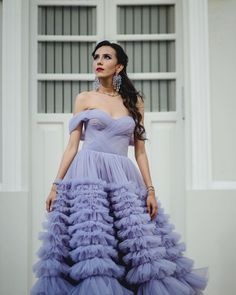 a woman in a purple dress is standing outside