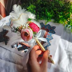 a person holding a pen with flowers and feathers on it