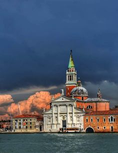 a large building sitting on top of a body of water under a cloudy blue sky