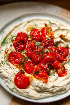 a white plate topped with hummus and tomatoes