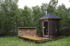 a small wooden outhouse sitting on top of a lush green field next to trees